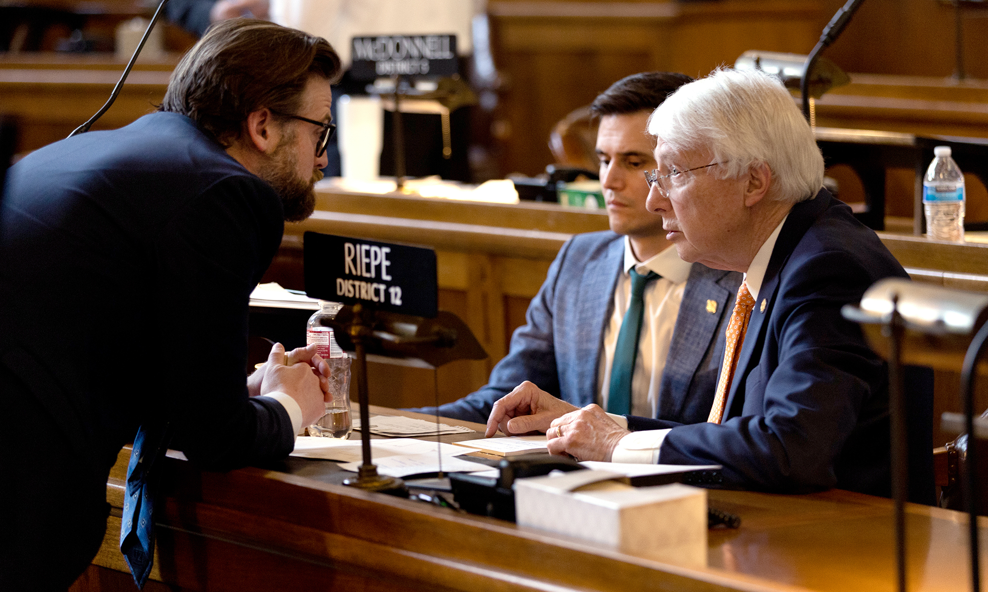 From left, Nebraska Sens. George Dungan III, John Fredrickson and Merv Riepe talk on the floor of the Legislature on April 26, 2023. Lawmakers debated a bill to ban abortion at approximately six weeks of pregnancy, but Riepe, a Republican, abstained from the vote, thus killing the bill. (Photo by Joseph Kual Zakaria/News21)
